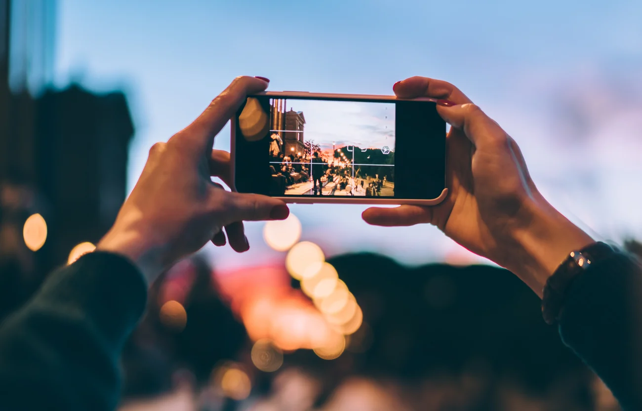夕暮れの街並みをスマートフォンで撮影する様子