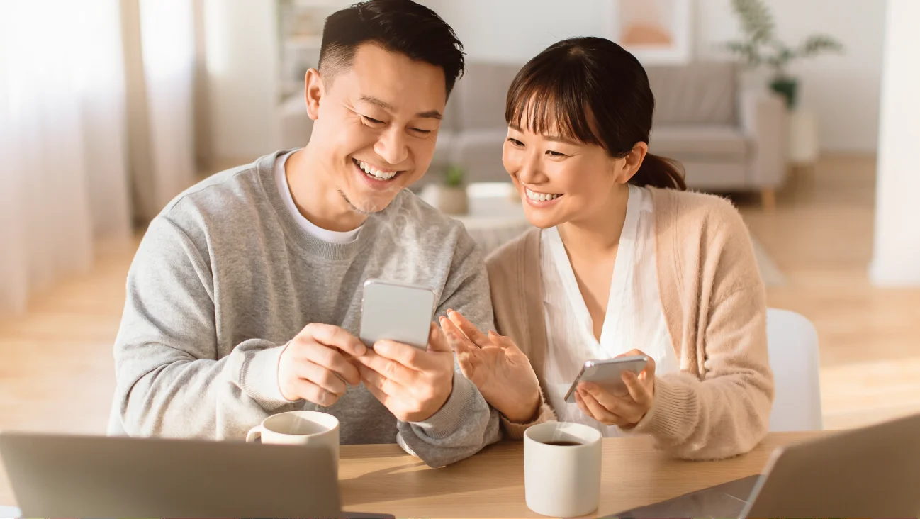 自宅でスマートフォンを見ながらくつろぐ夫婦